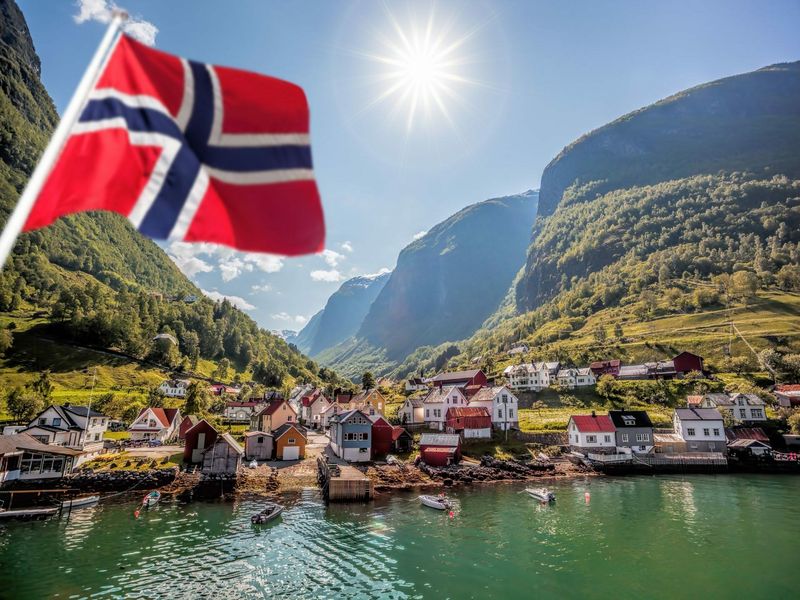 drapeau de la Norvège flottant avec en arrière plan un village